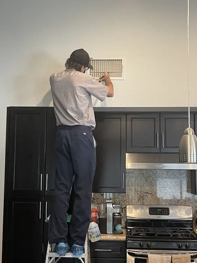 Technician inspecting an air vent during HVAC service in El Segundo